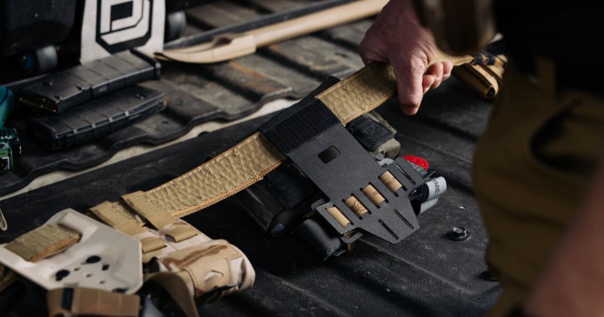 A man holding his battle belt with a Blue Alpha quick-detach drop mount attached.