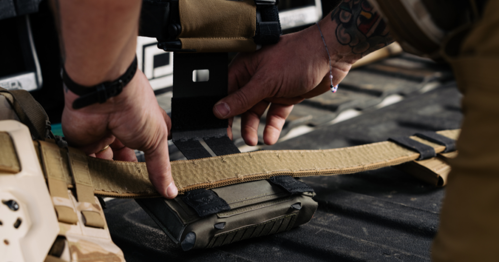 A man is adding a quick-detach drop mount from Blue Alpha onto his battle belt.