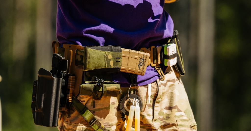 A man in a purple shirt using a horizontal mag pouch on his battle belt from Blue Alpha.