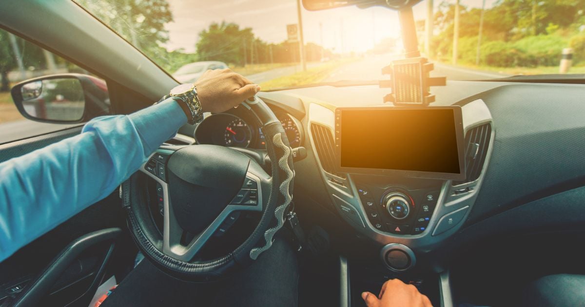 A man with a nice watch driving his car during a sunset.
