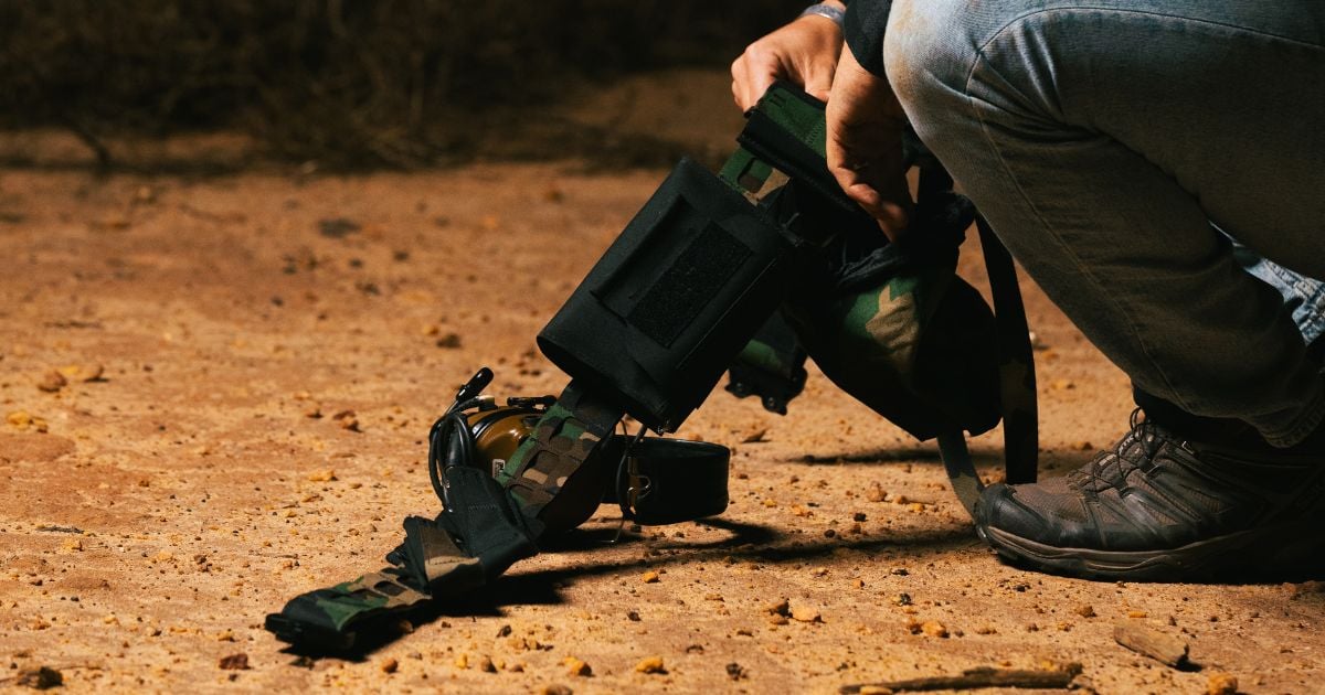 A man kneeling holding his everyday carry belt loadout.