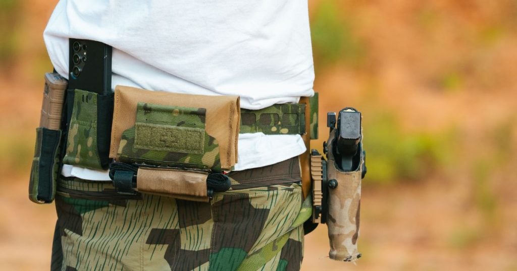 A man in green camo shorts wearing his Blue Alpha Battle Belt with a Med Pouch attached.