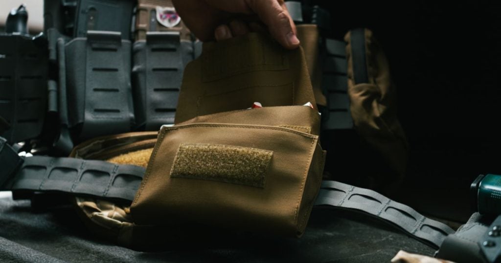 A person opening the Blue Alpha Medical Pouch that is low-profile.