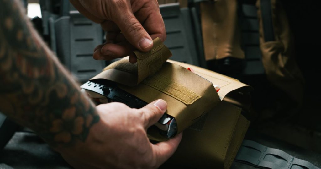 A man opening his Blue Alpha Medical Pouch.