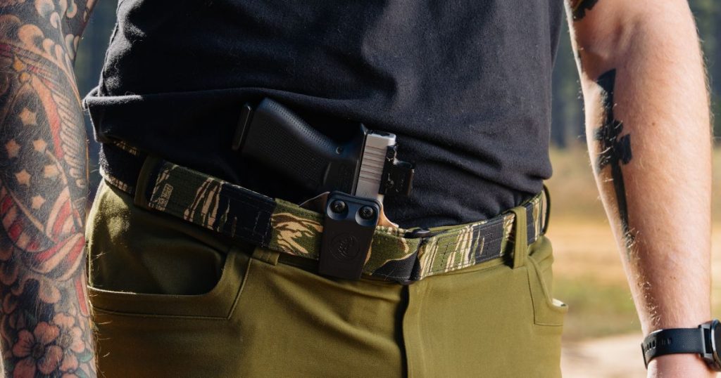 A man wearing a Blue Alpha EDC belt with a firearm tucked in at the center.