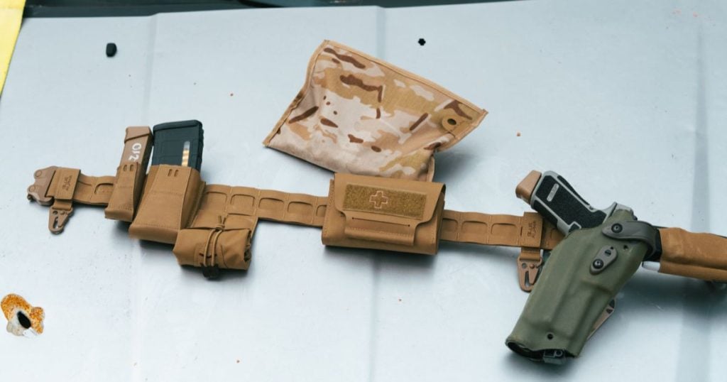 A Blue Alpha Battle Belt carrying a holder, magazine pouch and medical kit on a metal table.