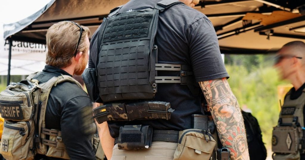 A man wearing a plate carrier with the +2 Blue Alpha adapter.